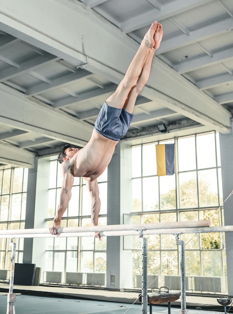 Free Photo male gymnast performing handstand on parallel bars