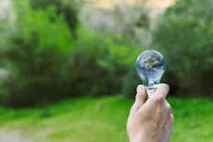 Free photo male hand holding earth in glass bulb