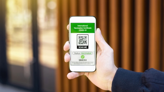 Male hand holding a smartphone with International Vaccination Certificate COVID-19 QR code