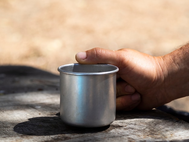 Free photo male hand holding vintage metal mug on sunny day