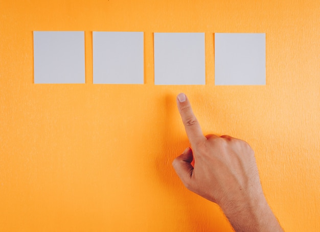 Male hand pointing to note papers on orange