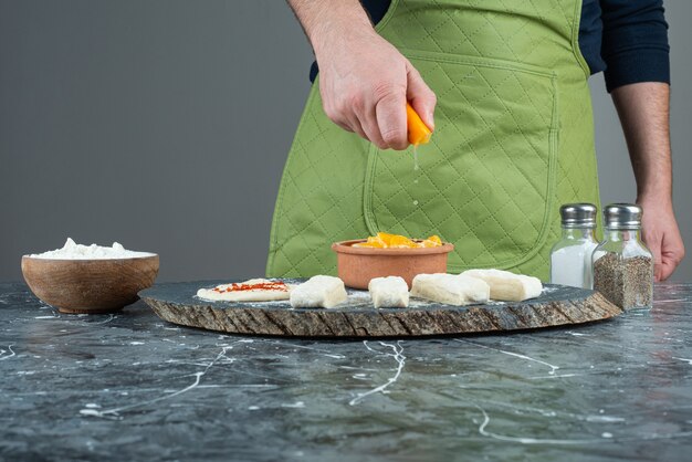 Free photo male hand squeezing lemon juice into the shrimps on marble table.