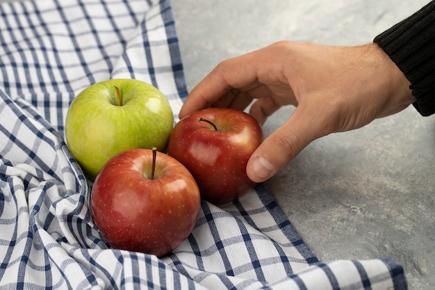 Male hand taking fresh red apple from marble.