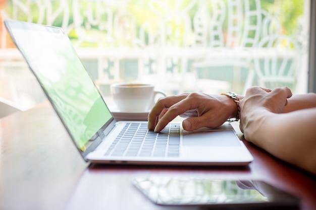 Male hand typing on laptop in cafe