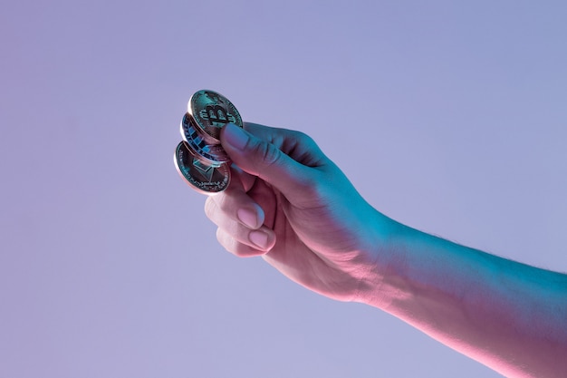 Male hand with golden bitcoin on blue background