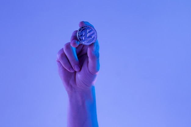 Male hand with golden Litecoin on blue background