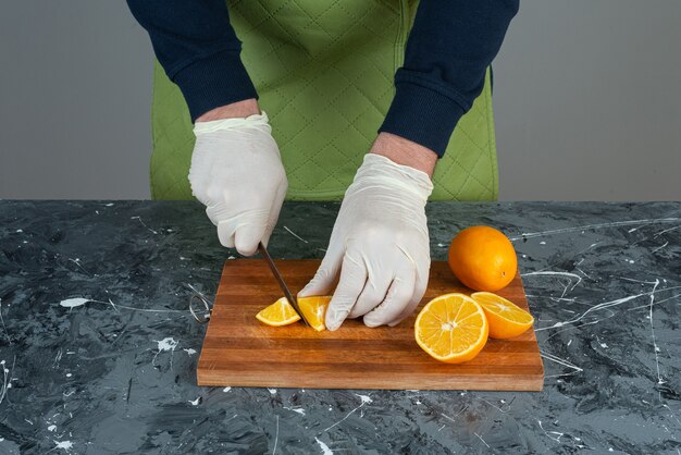 Male hands cutting fresh lemon on marble table.