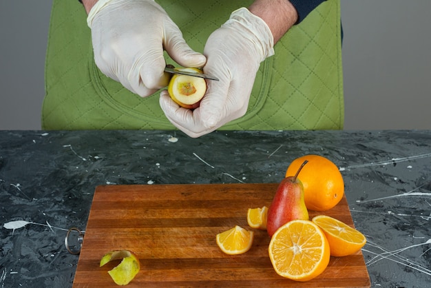 Free Photo male hands cutting ripe pear on marble table.