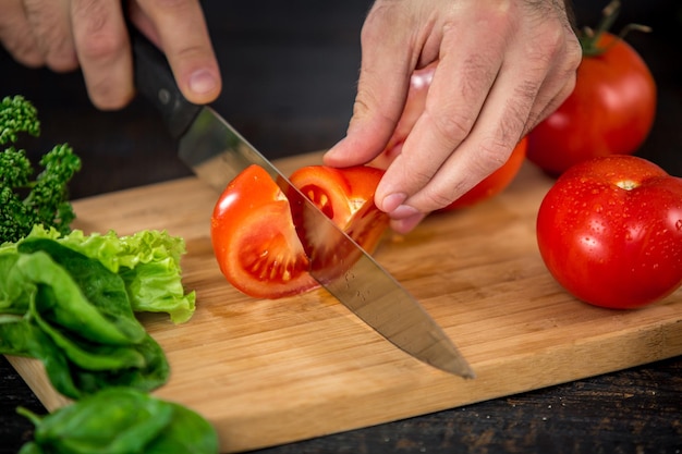 Male hands cutting vegetables for salad