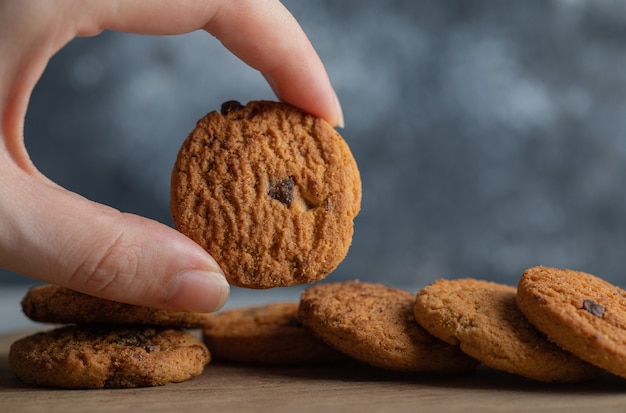 Free photo male hands holding delicious chocolate chip cookies on marble background