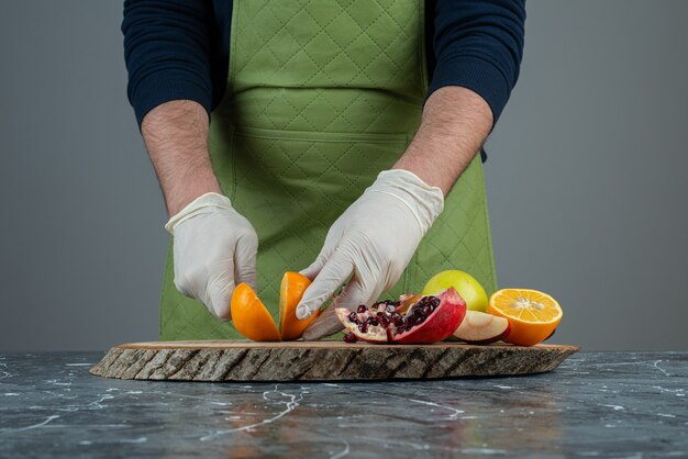 Male hands holding juicy orange on marble table.