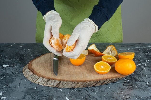 Free Photo male hands holding juicy tangerine on marble table.