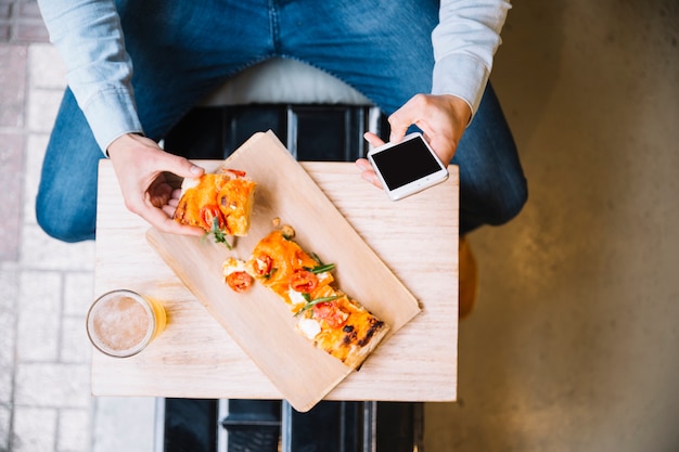 Male hands taking food and using smartphone