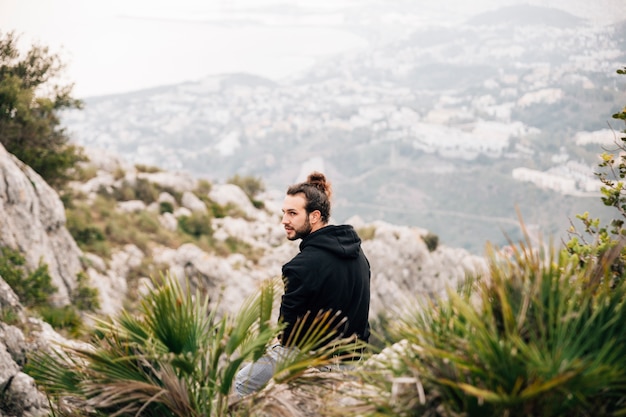 Free Photo a male hiker sitting on top of rocky mountain