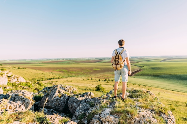 Male hiker standing on top of rock looking at green landscape