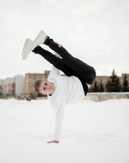 Free Photo male hip hop artist posing while dancing outside