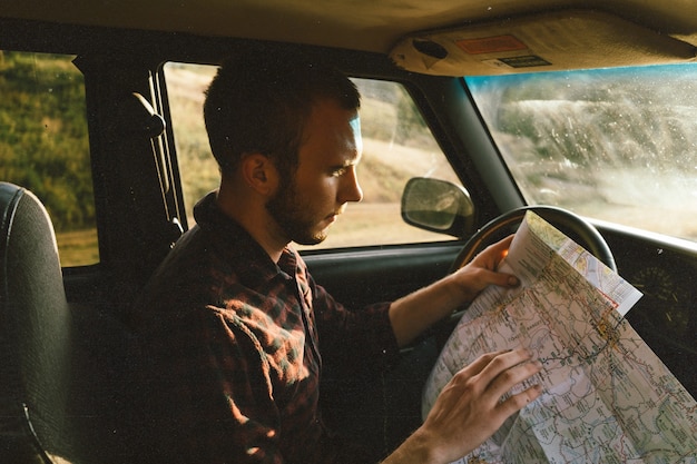 Free photo male in his vehicle looking at the map and deciding where to go