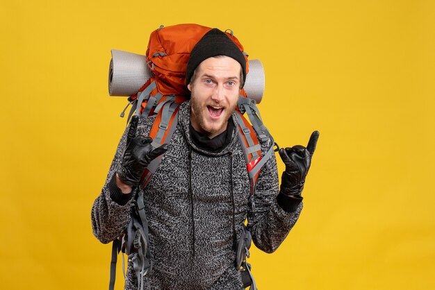 male hitchhiker with leather gloves and backpack making rock signs