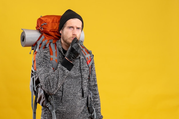 Free Photo male hitchhiker with leather gloves and backpack making shh sign