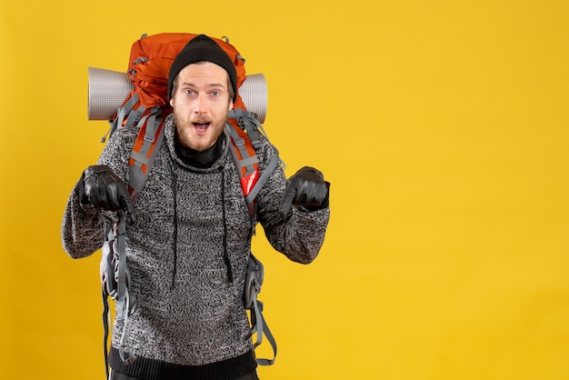 male hitchhiker with leather gloves and backpack pointing at floor