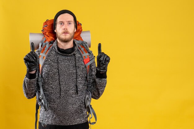 male hitchhiker with leather gloves and backpack pointing with fingers up