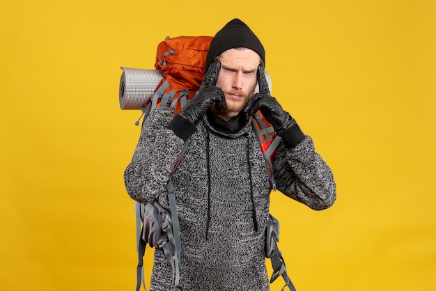 Free photo male hitchhiker with leather gloves and backpack putting fingers on his temple