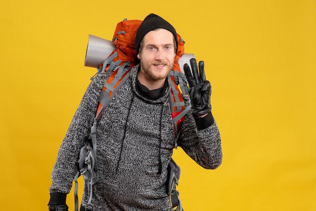 Free photo male hitchhiker with leather gloves and backpack showing three fingers