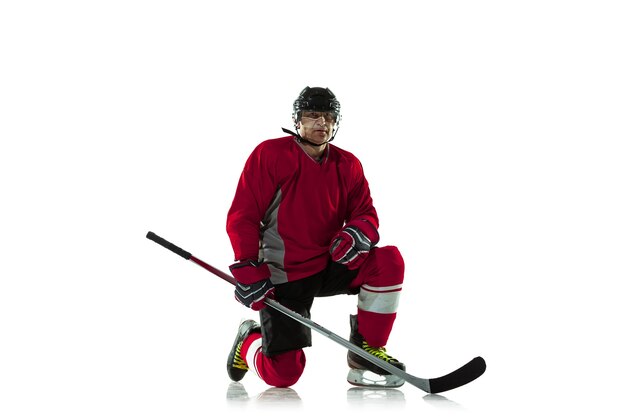 Male hockey player with the stick on ice court and white background.