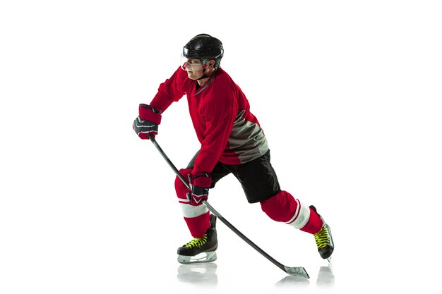 Male hockey player with the stick on ice court and white wall