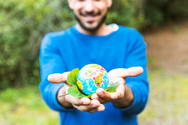 Free photo male holding globe with green leaf and smiling