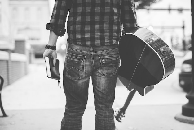 Free Photo male holding his guitar and a bible with a burred in black and white