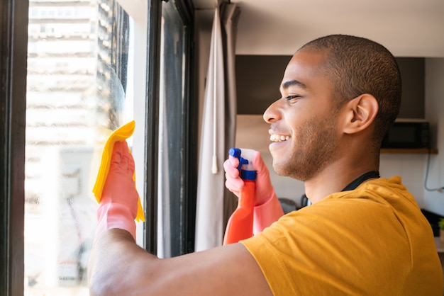 Male housekeeper cleaning glass window at home.