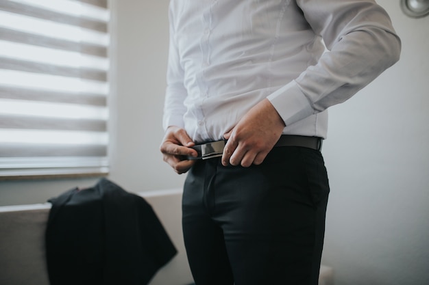 Free photo male is fastening black belt on his trousers