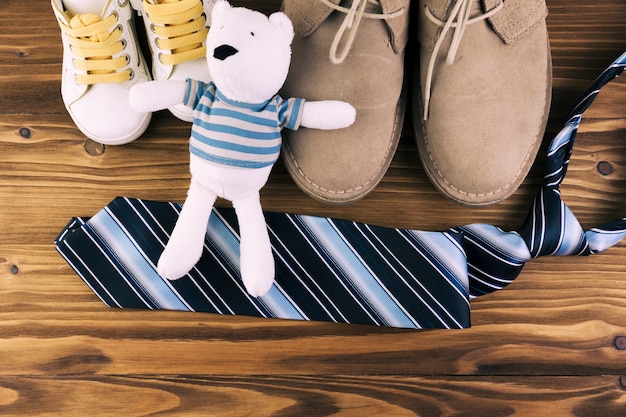 Free photo male and kid boots near tie with soft toy