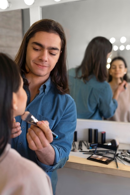 Male make-up artist putting on make-up on female client