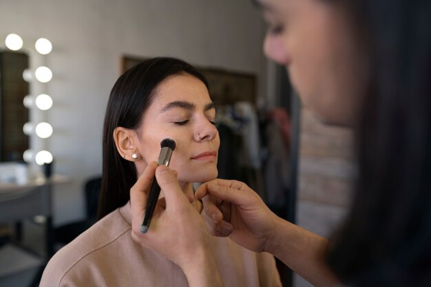 Male make-up artist putting on make-up on female client