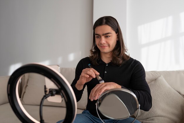 Male make-up artist putting on make-up on himself