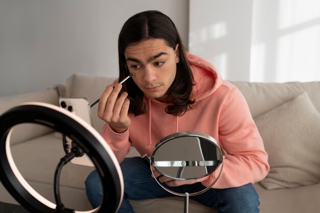 Male make-up artist putting on make-up on himself