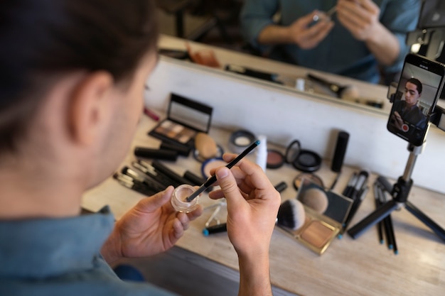 Free Photo male make-up artist putting on make-up on himself