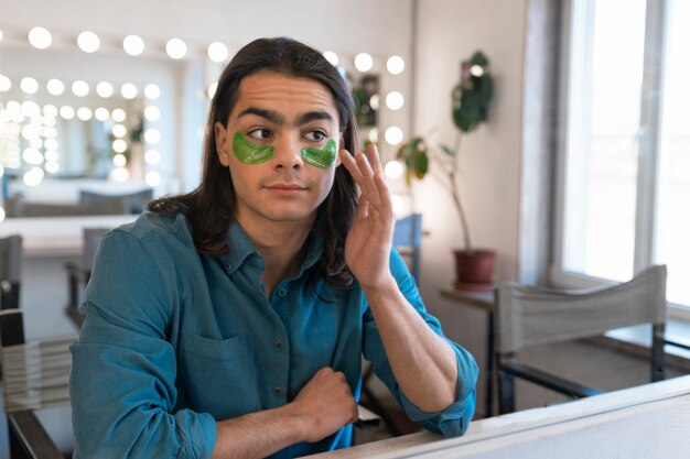 Free photo male make-up artist putting on make-up on himself