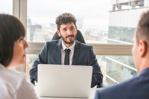 Male manager talking to businesspeople at workplace