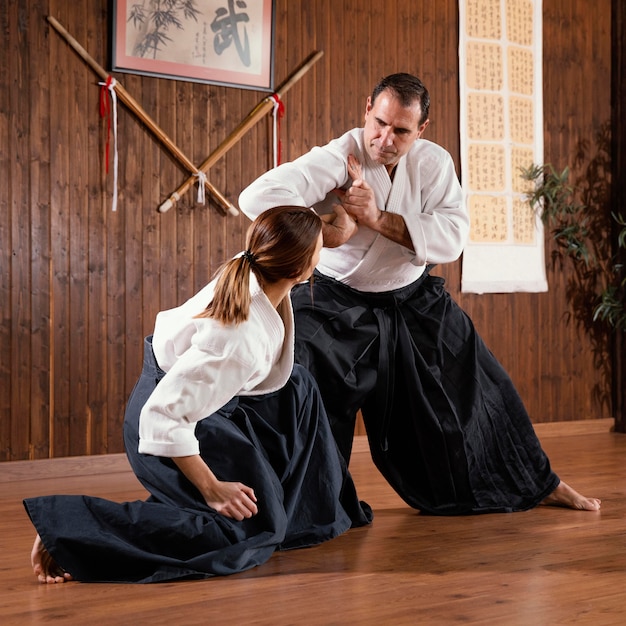 Male martial arts instructor training with trainee in practice hall