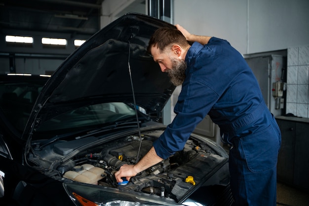 Free Photo male mechanic working in auto repair shop on car