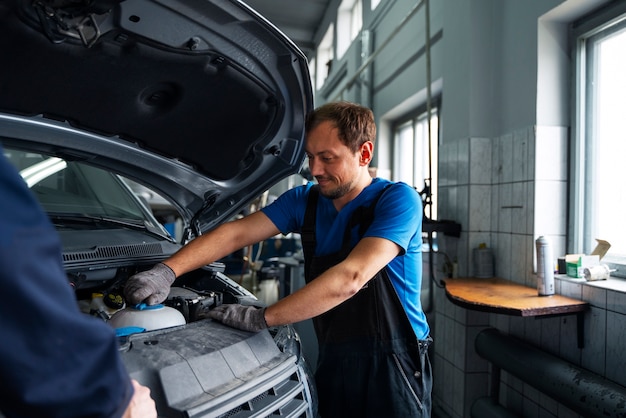 Free photo male mechanic working on car in the auto repair shop