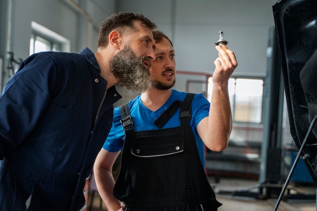 Free photo male mechanics working together on car in the shop