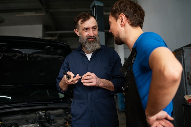 Free Photo male mechanics working together on car in the shop