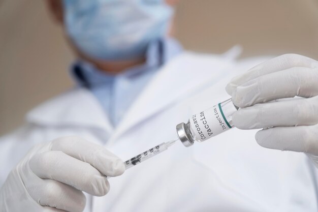 Male medic holding vaccine vial with syringe