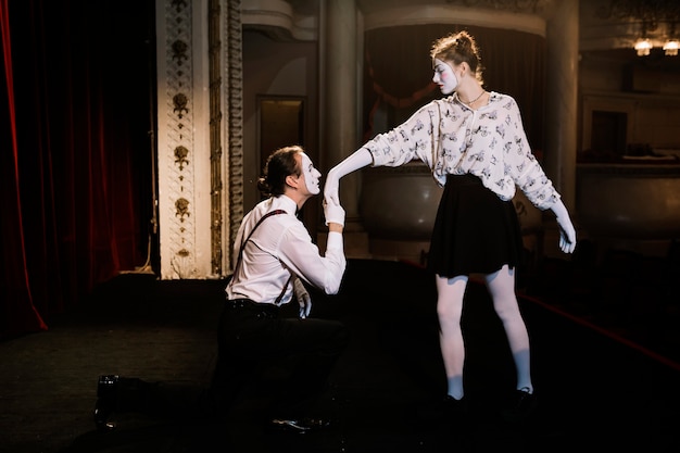 Male mime artist kissing to female mime's hand on stage