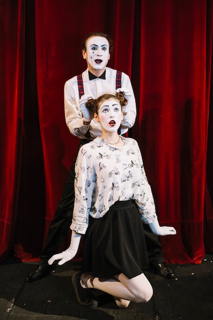 Free photo male mime artist placing his hand on female mime's hair buns