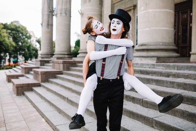 Free photo male mime carrying female mime on his back